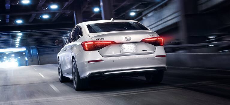 2027 Honda Civic Sedan Sport Touring Hybrid in Platinum White Pearl white rear view driving through tunnel (Compact Sedan)
